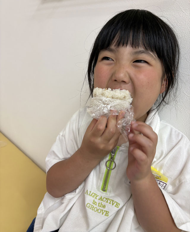【そのきおひさま食堂】おにぎりを食べる子供の写真